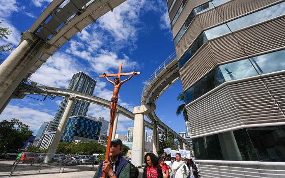 Ramon Ventura carries a crucifix as people walk from a downtown Miami Catholic church to the Miami Immigration Court to hold a prayer for immigrants, on the feast day of Mother Cabrini, patron saint of immigrants, Nov. 13, 2025. (AP/Rebecca Blackwell)