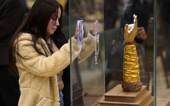A woman prays in front of a glass-encased reliquary containing a bone from the arm of St. Jude the Apostle at St. Jude Church in Mastic Beach, N.Y., Nov. 27, 2023. (OSV News/Gregory A. Shemitz)