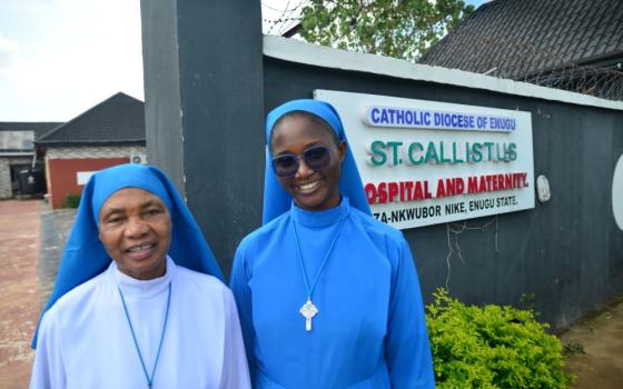 Daughters of Divine Love Srs. Mary Calisata Iwuji and Jacinta Nwankwo pose for a photo in front of the diocesan clinic in Ezza-Nkwubor Nike, a remote village in Enugu State, southeast Nigeria. (Patrick Egwu)