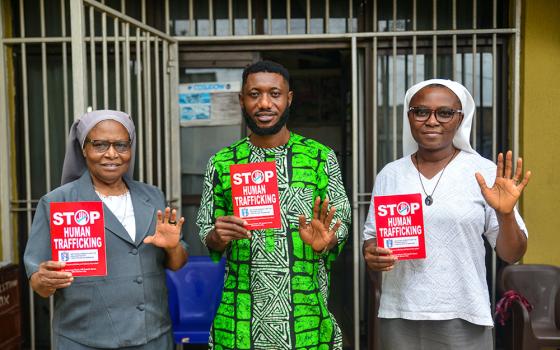 From left, Sr. Justina Odunukwe, Wisdom Ugochukwu Umunakwe, and Sr. Helen Omeya display an anti-trafficking poster outside the office of the Committee for the Support of the Dignity of Women in Benin City, Nigeria. (Patrick Egwu) 