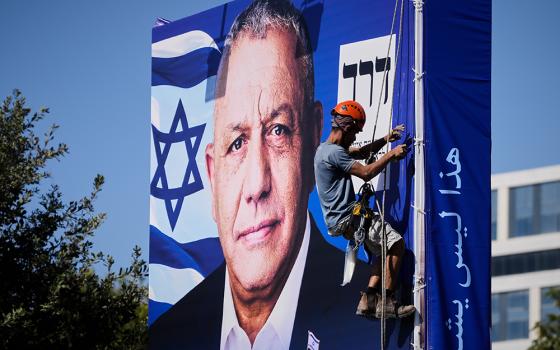 A worker hangs a campaign billboard featuring Gadi Eisenkot, leader of Yashar ("Straight") party, ahead of Israel's general election in Jerusalem, Oct. 22, 2026. (AP photo/Ohad Zwigenberg)