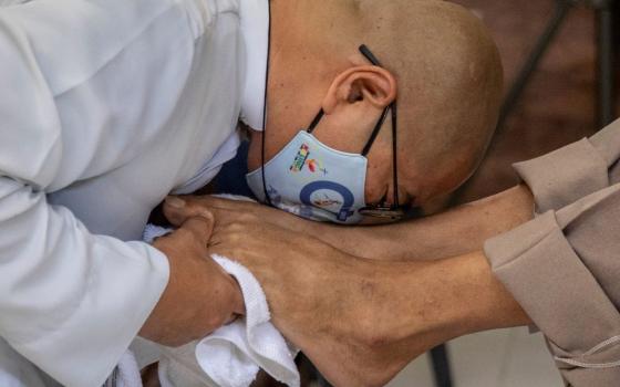 Fr. Flavie Villanueva, a member of the Society of the Divine Word, kisses the feet of a homeless man after washing them Holy Thursday in Manila, Philippines, April 1, 2021. (CNS/Reuters/Eloisa Lopez)