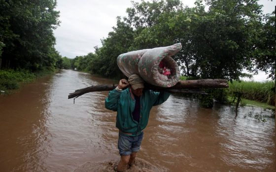 A man carries his belongings through a flooded road in Marcovia, Honduras, Nov. 18, after the passing of Hurricane Iota. (CNS/Reuters/Jorge Cabrera)