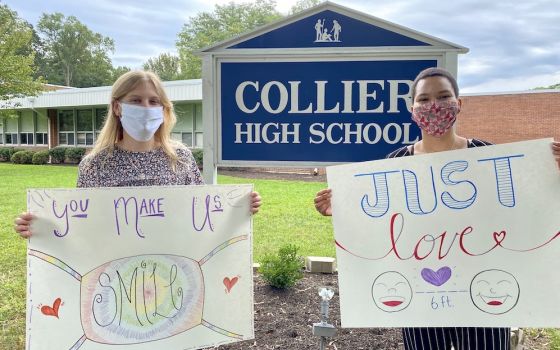 Maddie Thompson, left, and Madison Thomas, a former Good Shepherd Volunteer, pose with their welcome signs outside of Collier High School in Wickatunk, New Jersey. (Christina Hardebeck)