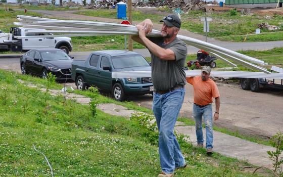 Eric Shelburne, left, and Ronnie Mattingly carry trim to a house where the Sisters of Charity of Nazareth's disaster recovery team is helping a family rebuild May 23 after a devastating tornado in Mayfield, Kentucky. (GSR photo/Dan Stockman)