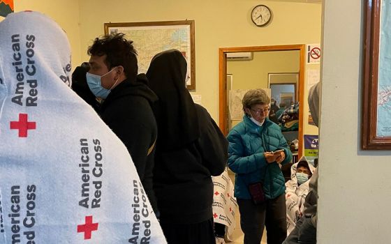 Sr. Judy Bourg (in green coat), a School Sister of Notre Dame, speaks with volunteers and returned migrants on an early morning in October 2021 at the migrant resource center in Agua Prieta, Mexico. (Peter Tran)