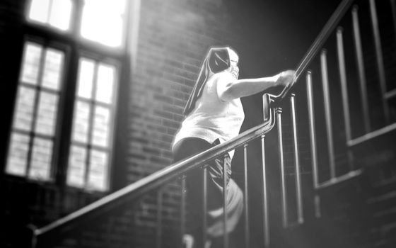 Felician Sr. Mary Ann Smith climbs a staircase in the Felician Sisters' convent in Livonia, Michigan, in June 2020 in this photo illustration. (GSR illustration/Dan Stockman)