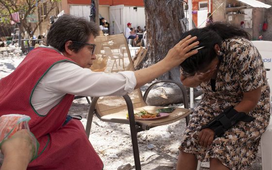 Sr. Mercedes Castillo prays over a Peruvian woman who only wanted to be known by the initials A.N. in the courtyard of the El Buen Samaritano shelter in Nuevo Laredo, Mexico, on March 27. (Nuri Vallbona)