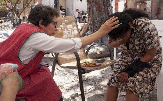 Sr. Mercedes Castillo prays over a Peruvian woman who only wanted to be known by the initials A.N. in the courtyard of the El Buen Samaritano shelter in Nuevo Laredo, Mexico, on March 27. (Nuri Vallbona)