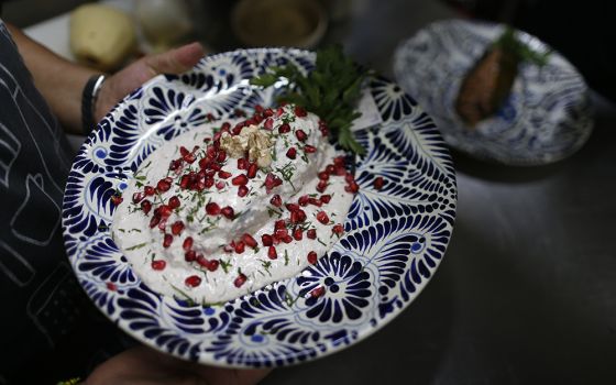 A cook carries out a plate of chiles en nogada to be served to diners at Testal restaurant in downtown Mexico City in September 2019. The recipe was invented in 1821 by a nun whose name has been lost to history. (AP Photo/Rebecca Blackwell, File)
