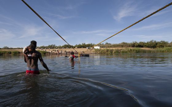 Haitian immigrants make their way along a rope suspended above the Rio Grande on their way to the United States Sept. 22. (Nuri Vallbona)