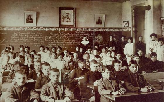 Sr. Macaria Murphy, a Franciscan Sister of Perpetual Adoration, poses with students and lay staff in a classroom at St. Mary's Catholic Indian Boarding School in Odanah, Wisconsin, in this undated photo. (Courtesy of FSPA)