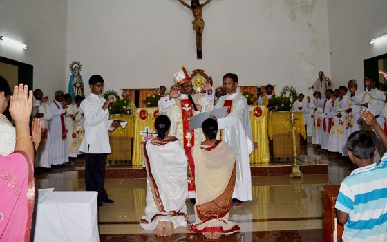 Srs. Sujata Jena and Goretti Nayak receive solemn blessings from Archbishop John Barua during their final vows as members of the Congregation of the Sacred Hearts of Jesus and Mary on Oct. 11, 2014, at St. Vincent Catholic Church in Bhubaneswar, Odisha