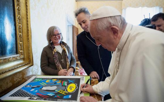 Comboni Missionary Sr. Gabriella Bottani, international coordinator of Talitha Kum, and artist Stephen Powers, also known as ESPO, watch Pope Francis sign a print of Powers' art. (Provided photo)