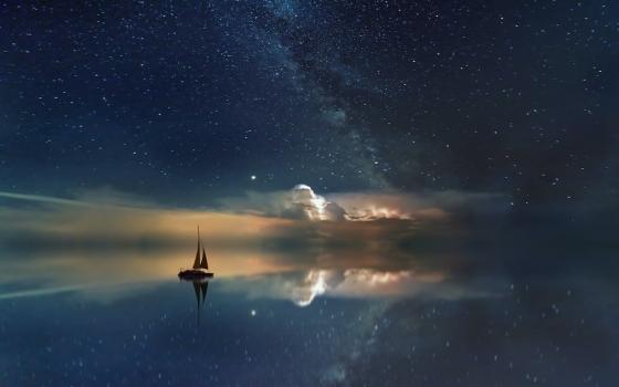 A silhouetted sailboat in the night under the stars (Unsplash/Johannes Plenio)