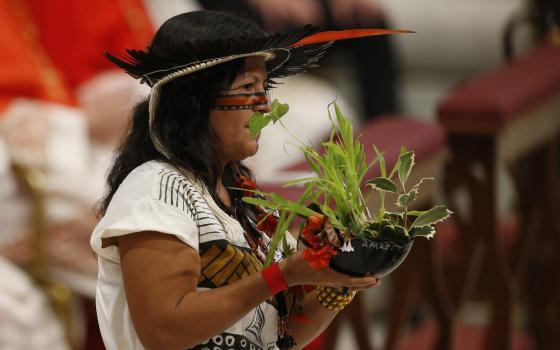 Marcivana Rodrigues Paiva, representing the Satere-Mawe indigenous people in Brazil, carries a plant in the offertory procession as Pope Francis celebrates the concluding Mass of the Synod of Bishops for the Amazon at the Vatican Oct. 27, 2019. (CNS photo