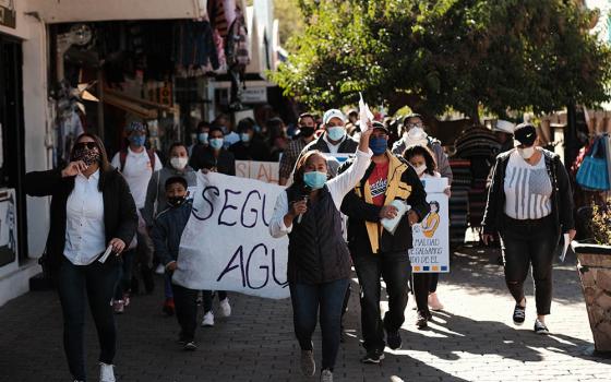 Migrant families participate Dec. 2 in the #SaveAsylum March through downtown Nogales, Sonora, Mexico. Their banner reads "Seguimos Agui" ("We're Still Here").  (Provided photo)