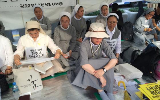 Women religious sit Tuesday with families of those who died in the April 16 sinking of a ferry to show support for an independent investigation of the disaster. The families have been protesting in the Seoul, South Korea, plaza where Pope Francis is to beatify 124 martyrs for 30 days. (NCR Photo/Thomas C. Fox)