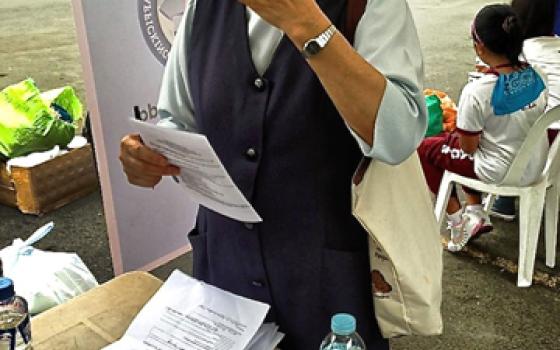 A nun reads through an anti-trafficking leaftlet handed out to Typhoon Haiyan survivors at the Philippine Air Force Base in Pasay City, Philippines, beginning Nov. 16. (Courtesy of Inter-agency Council Against Trafficking)