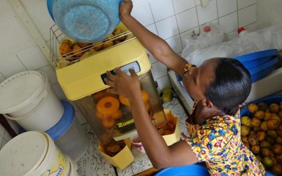 Sr. Mary Boatemaa loads the orange juicer with oranges. (GSR/Dana Wachter)