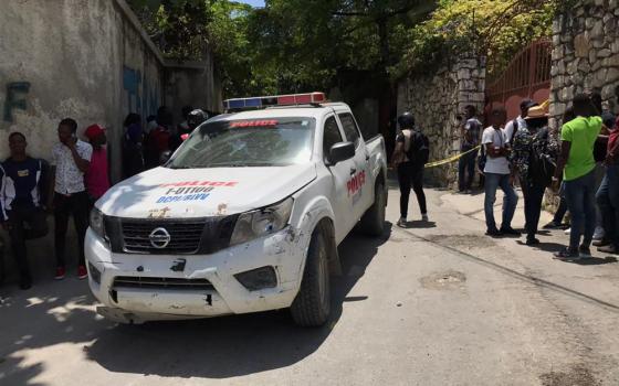 People stand next to a police car and a yellow police cordon near the residence of Haitian President Jovenel Moïse near Port-au-Prince July 7. The president was assassinated in an early morning attack at his home, the prime minister said. (CNS/Reuters/Est