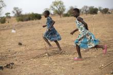 Children in Ghana run together through a dry field that has been severely affected by irregular weather patterns caused by climate change. (CNS/Courtesy of Catholic Relief Services/Jake Lyell)
