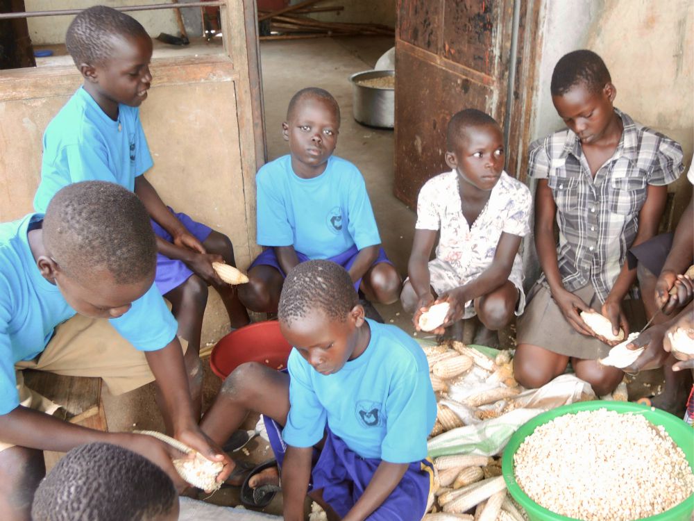 South Sudanese students at the Bishop Caesar Asili school who live in a nearby settlement help prepare lunch during the school vacation