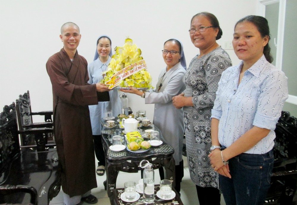 Sr. Anna Nguyen Thi Hien (third from left), another sister and lay volunteers offer flowers to Venerable Thich Tam Quang, a Buddhist monk and clinic director, at Hai Duc Clinic on May 6. (Joachim Pham)