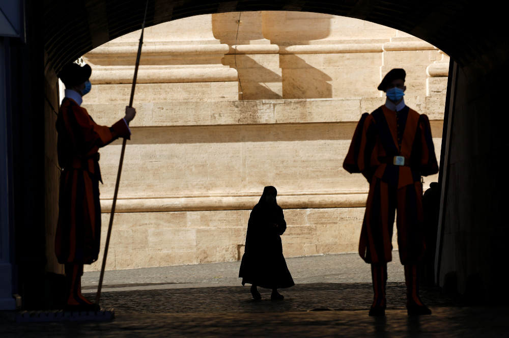 Swiss Guards stand at attention as a nun passes by at the Vatican Nov. 9, 2020. (CNS/Reuters/Remo Casilli)