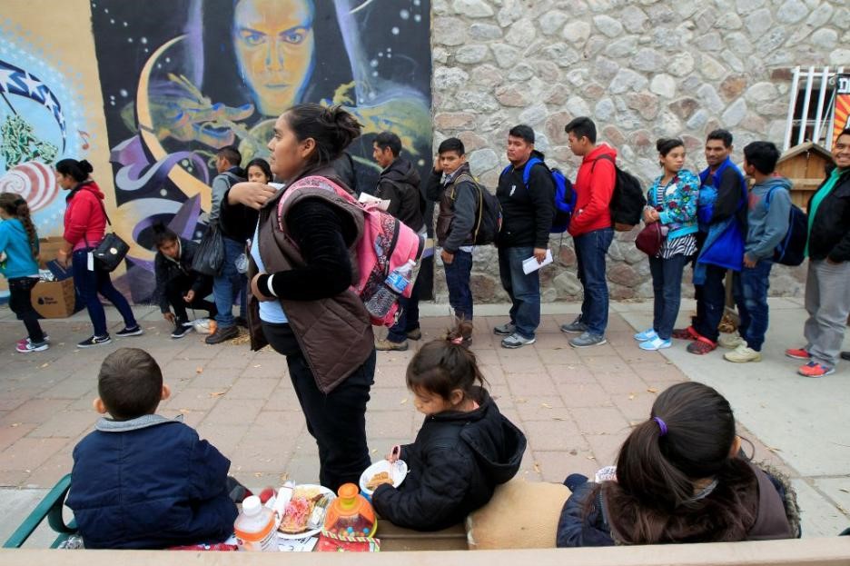 Migrants in El Paso await transportation to emergency shelters.